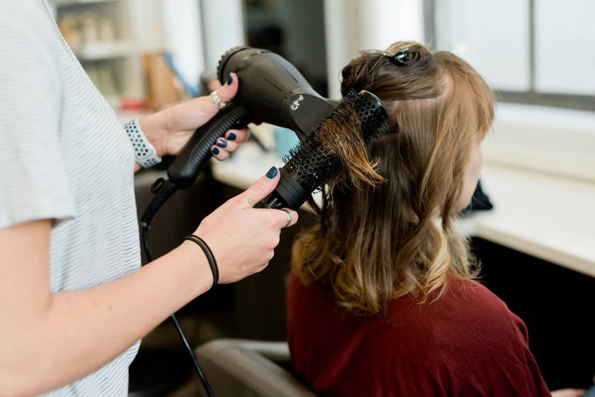 Step-by-step visual demonstrating updo bun techniques with hands shaping a low chignon on textured hair